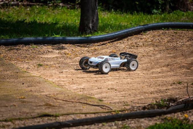 Buggy RC branco contornando pista de terra