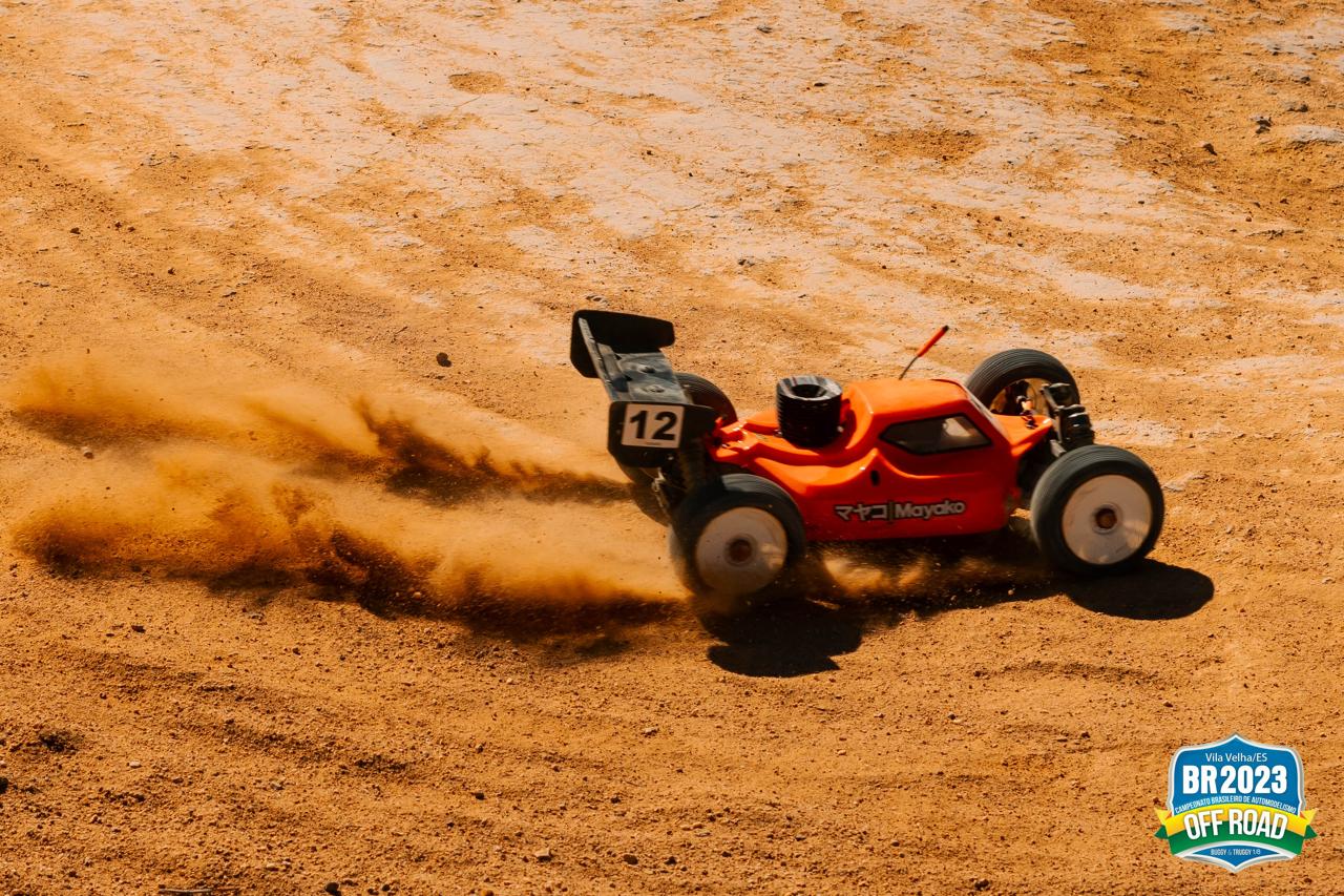 Buggy RC vermelho levantando poeira em pista off-road